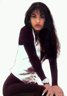 a woman sitting on top of a stool wearing black and white shirt with long sleeves