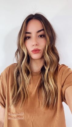 a woman with long wavy hair is looking at the camera