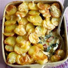 a casserole dish with potatoes and spinach in it on a checkered table cloth