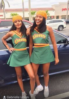 two women in green cheerleader outfits standing next to a car