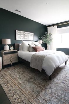 a bedroom with a large bed and rug on the floor in front of a window