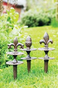 three wrought iron fence posts in the grass