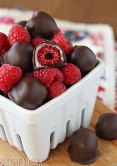 a white bowl filled with chocolate covered raspberries