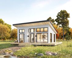 a small white house sitting on top of a lush green field next to a forest