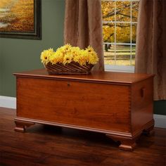 a basket with flowers sitting on top of a wooden chest in front of a window