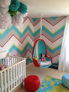 a baby's room decorated in blue, pink and green with a swing chair