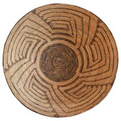 a brown and black woven basket on a white background with an intricate design in the center