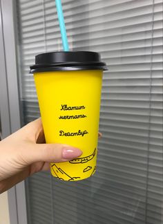 a person holding up a yellow cup with a straw in it