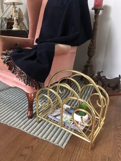 a pink chair with a black blanket on top of it next to a magazine rack