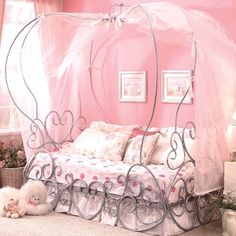 a pink bedroom with a canopy bed and two small white dogs laying on the floor