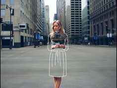 a woman standing in the middle of an empty street holding a cell phone and wearing a white dress