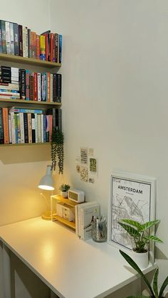 a white desk topped with a lamp next to a bookshelf filled with books