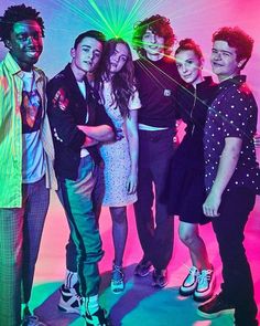 a group of young people standing next to each other in front of a neon colored background