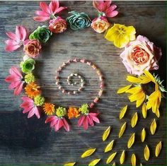 flowers arranged in the shape of a circle on a wooden table with beads and pearls