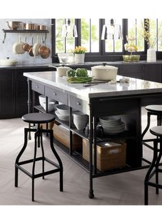 a kitchen island with lots of counter space and stools around it in front of windows