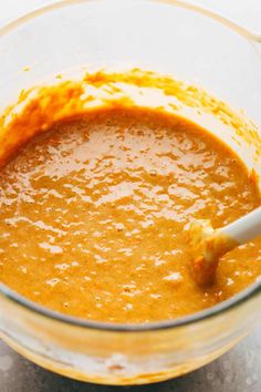 a glass bowl filled with orange sauce on top of a table