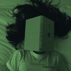 a person laying in bed with a box on top of their head and hair flying around