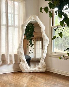 a mirror sitting on top of a hard wood floor next to a potted plant