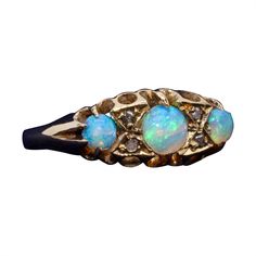 An antique opal, diamond, and yellow gold ring, comprising three round opal cabochons, and four rose cut diamonds, set in 18 karat yellow gold, to a band of 18 karat yellow gold. This ring is set with 3 round cabochon white opals. The opals are beautifully colourful, exhibiting vibrant aqua, green, blue, and purple, with flashes of warm red and yellow. The two smaller opals are particularly beautiful and very well-matched with one another. Small rose cut diamonds intersperse the opals, adding a Antique Rings Victorian, Opal And Diamond Ring, Opal Ring Vintage, Rose Cut Diamond Ring, Opal Diamond Ring, Rosecut Diamond Ring, Edwardian Jewelry, Opal Ring Gold, Victorian Rings