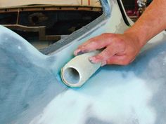 a man is waxing the hood of a car with a blue substance on it