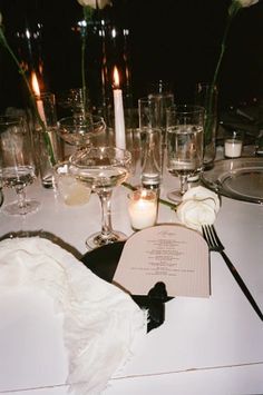 the table is set with wine glasses, candles and napkins for an elegant dinner