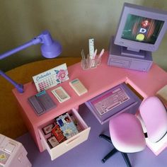 a toy desk with a computer and various items on it, including a pink chair