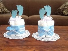 two baby feet on top of a cake with blue ribbon and white frosting, sitting on a table in front of a couch