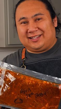 a man holding up a bag of food with writing on the side and an orange ribbon around his neck