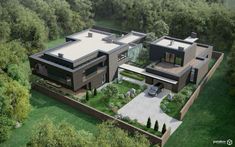 an aerial view of a modern house in the middle of trees and grass, with two cars parked on the driveway