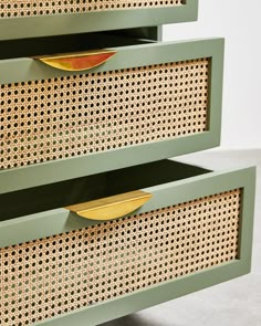 two green drawers with gold handles on each drawer and perforated metal inserts