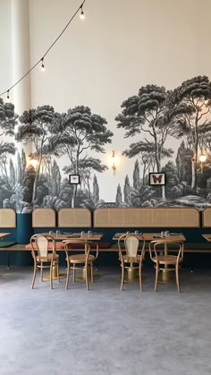 an empty restaurant with tables and chairs in front of a wall mural that has trees on it