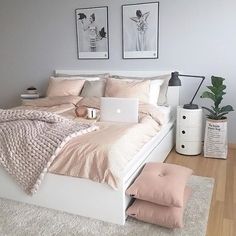 a white bed sitting in a bedroom next to a laptop computer