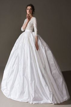 a woman in a white wedding dress posing for the camera with her hand on her chin