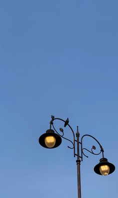 an airplane flying in the blue sky above two street lights