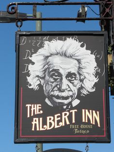 the albert inn sign is hanging from an old fashioned metal pole with graffiti on it