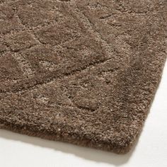 a close up view of a brown rug on the floor with white walls in the background