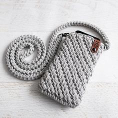 a gray crocheted purse with a brown button on the side and a white cord attached to it