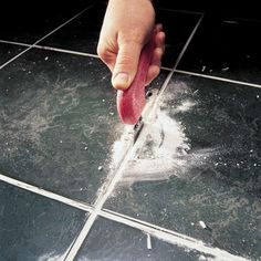 a hand holding a piece of food on top of a tiled floor with water coming out of it