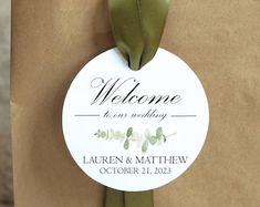 a welcome sign is attached to a brown paper bag with a green ribbon on it