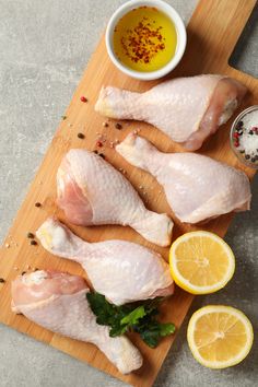 raw chicken on a cutting board with lemons and spices