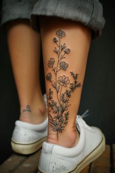 a woman's legs with flowers tattooed on the lower part of her leg and foot