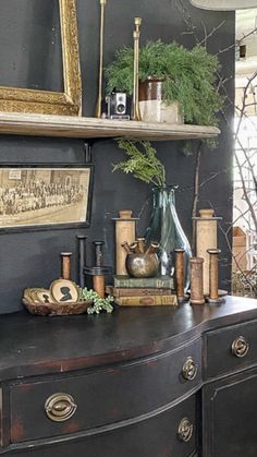 an old dresser with various items on it and framed pictures above the top, along with other antiques