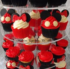 cupcakes with red and white frosting are arranged in a tiered display