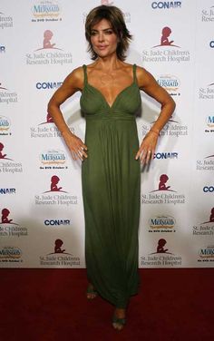 a woman in a green dress standing on a red carpet with her hands on her hips