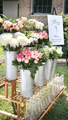 many vases with flowers are lined up on a table in front of a house