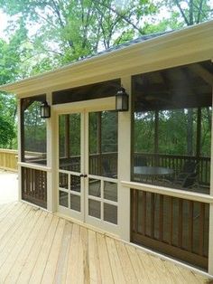 a screened porch with sliding glass doors and wood flooring on the side of it