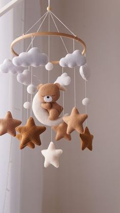 a teddy bear is sleeping on the moon and stars mobile for baby's crib