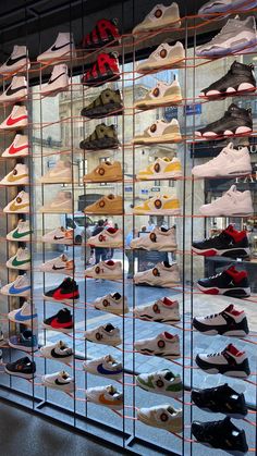 many pairs of shoes are on display in a glass case with metal bars around them