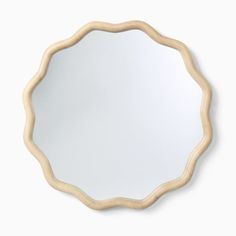 a round mirror on the wall with a wooden frame and an oval shaped design around it