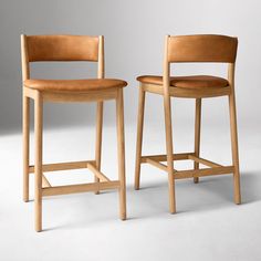 two wooden stools sitting next to each other on a white floor with grey background